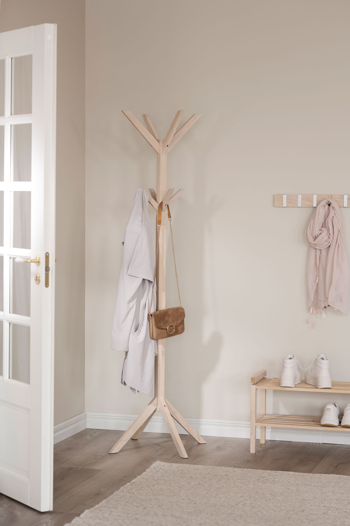 Confetti Klädhängare/Tumburmajor av vitpigmenterad ek placerad i en ljus skandinavisk hall med mörkbrunt golv och ljusbeige väggar